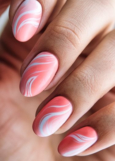 Elegant coral pink almond nails with artistic white marble designs and matte finish.