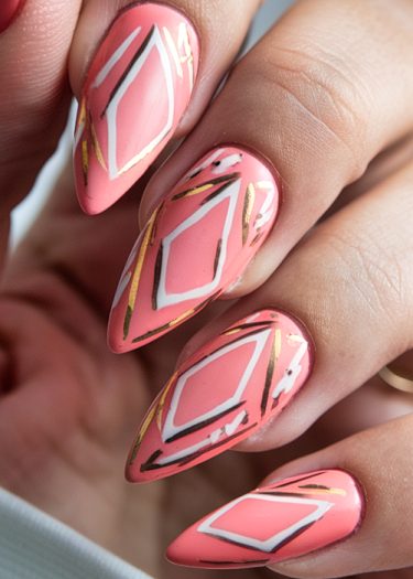 Stylish coral pink stiletto nails featuring luxurious gold and white geometric patterns.