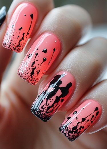 Stunning coral nail art with black splatter and silver accents for a bold, trendy look.