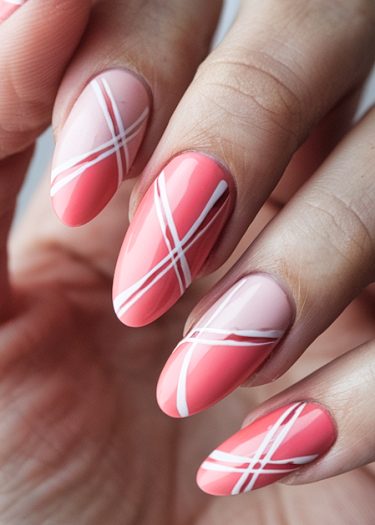 Elegant coral pink nail art with white diagonal stripes for a modern manicure look.