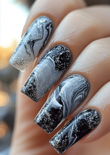 Elegant marbled black, white, and gray nails with silver glitter for a stunning manicure.