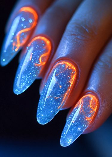 Cosmic blue stiletto nails with glowing orange nebula design and starry sparkle details.