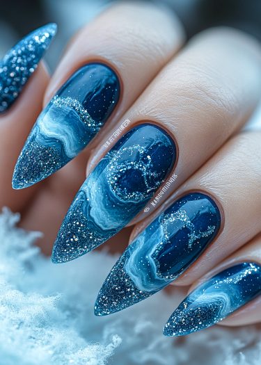 Elegant cosmic ocean nail art with navy blue stiletto nails and shimmering glitter design.