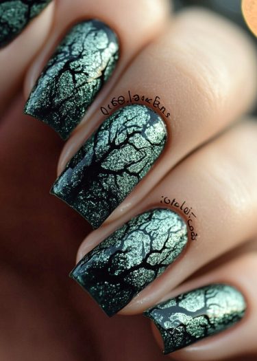 Intricate cracked metallic nail art design on dark nails offers a bold, stylish statement.