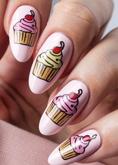 Gorgeous pastel pink nail art featuring whimsical cupcake designs with colorful frosting.