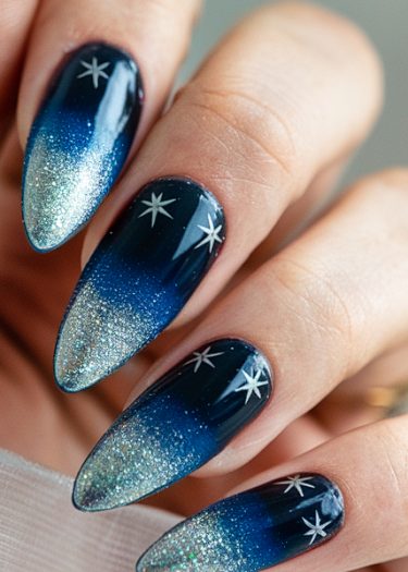 Elegant midnight blue ombre nails with shimmering silver gradient and star designs.