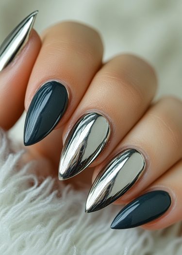 Stunning stiletto nails in metallic chrome and glossy charcoal, set against a plush background.