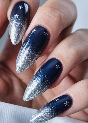 Stunning dark blue stiletto nails with silver gradient and star decals for a celestial look.