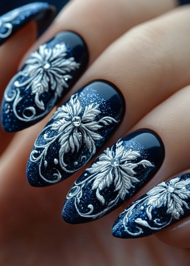 Elegant navy blue floral nail art with silver design and sparkling gems for a sophisticated look.