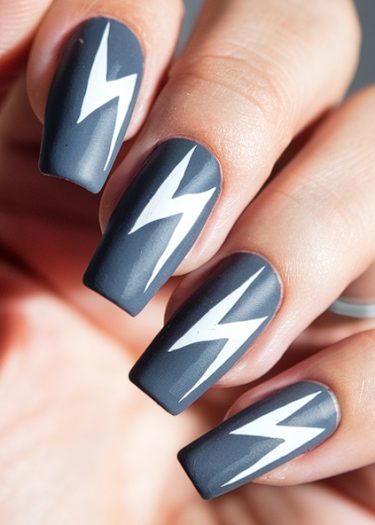 Matte dark gray nails with bold white lightning bolt art for trendy nail designs.