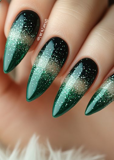 Elegant stiletto nails with dark green gradient and shimmering glitter for a luxurious manicure.