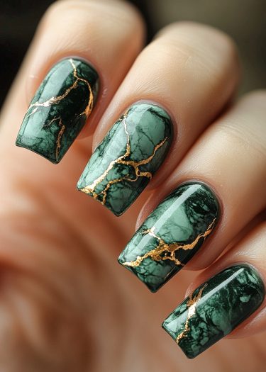 Elegant dark green marble nail design with gold accents for a luxurious, sophisticated look.