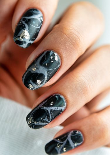 Elegant dark marble nail art featuring intricate white veining and luxurious gold accents.