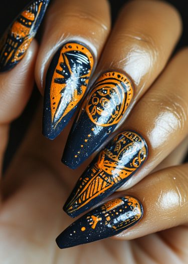 Intricate matte black and vibrant orange tribal nail art with stiletto shape and celestial designs.