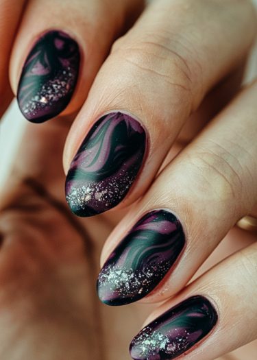 Elegant dark purple almond nails with marbled design and glitter accents for a cosmic look.