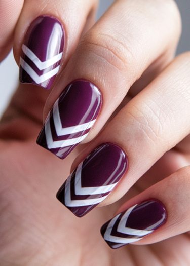 Stylish dark purple nails with chevron design showcase modern manicure elegance.