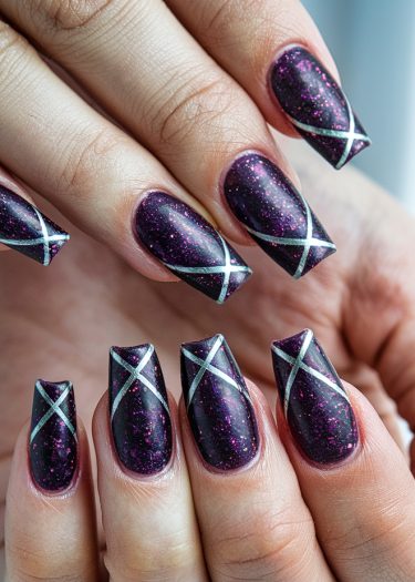 Stunning dark purple galaxy nails with silver lines and glitter, showcasing elegant nail art.