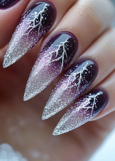 Elegant stiletto nails with a black to icy silver gradient and intricate silver designs.