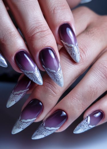 Elegant burgundy almond-shaped nails with intricate silvery lace tips for a luxurious look.