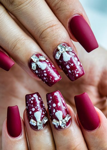 Elegant dark red matte nail art with intricate silver and white embellishments.