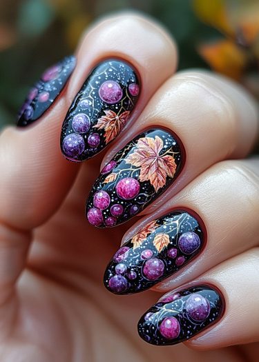 Elegant autumn nail art featuring black base, grapes, and vibrant fall leaves design.