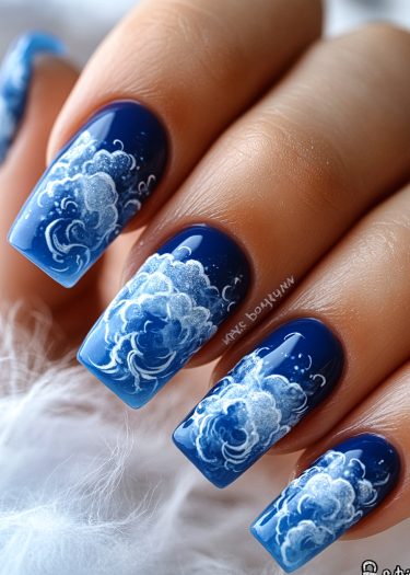 Stunning deep blue cloud nail art with detailed swirling designs and glossy finish.