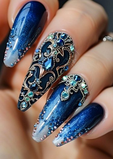 Elegant deep blue gemstone nail art with intricate designs and sparkling glitter for a luxurious look.