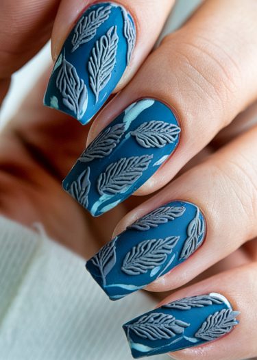 Elegant deep blue nail art with embossed leaf designs for a sophisticated look.