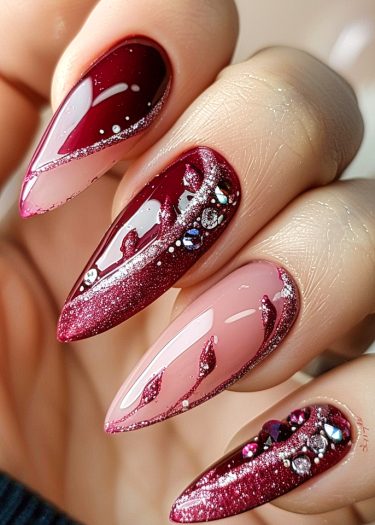 Elegant deep crimson nail design with glitter and rhinestones for a luxurious manicure.