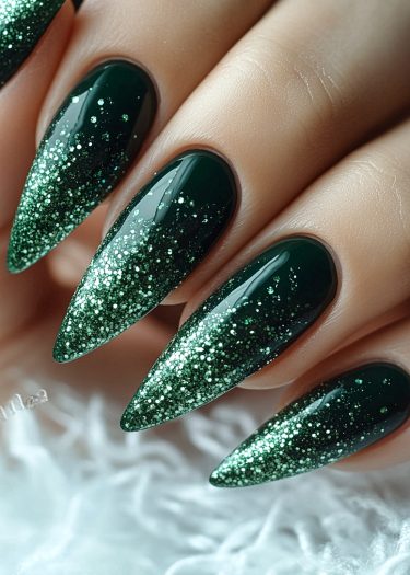 Elegant stiletto nails with deep green polish and shimmering glitter design.