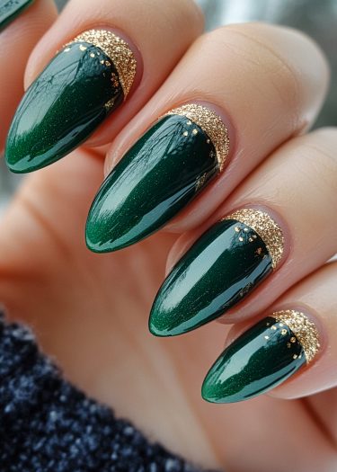 Elegant deep green and gold nail art with manicured almond-shaped design.