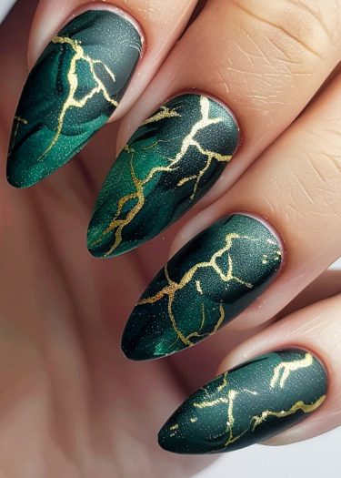 Elegant emerald green nails with golden marbling for a chic nail art design.