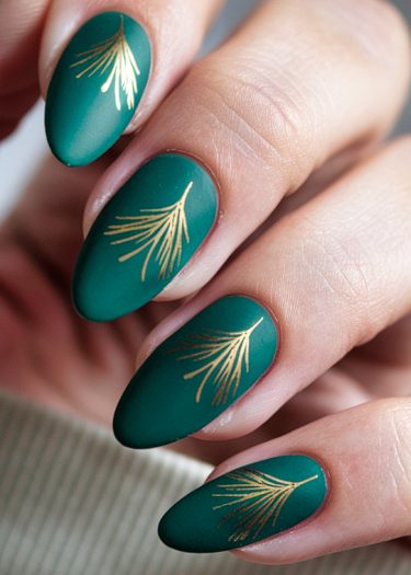 Elegant deep green almond nails with gold pine branch designs in a sophisticated matte finish.