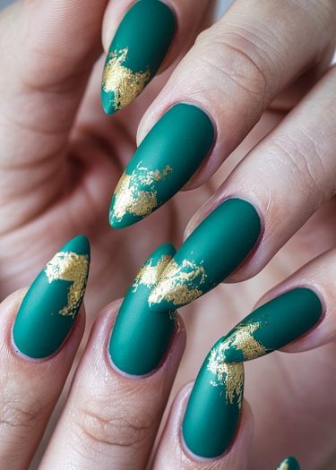 Elegant matte teal almond-shaped nails with gold foil accents in artistic patterns.