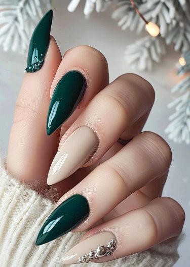 Elegant deep green and nude manicure with stiletto nails, featuring intricate silver embellishments.