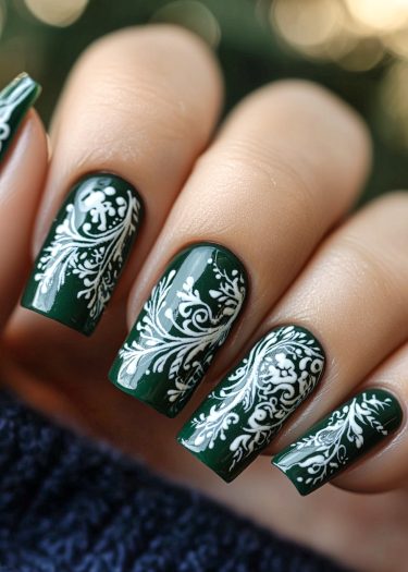 Elegant deep green nails with intricate white vine and floral nail art design.