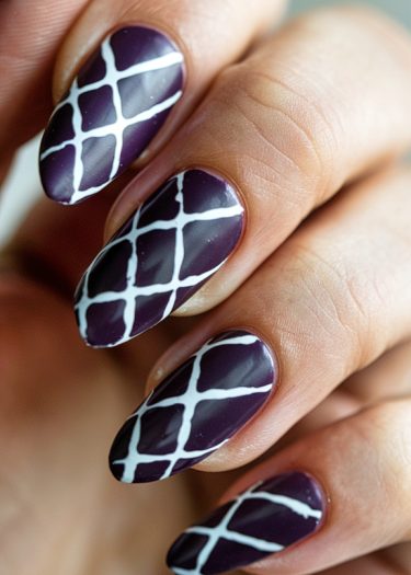 Stylish deep purple nail art with elegant white crisscross geometric design for a chic look.