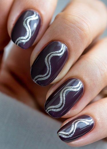 Elegant deep purple glossy nails with metallic silver design for a stylish manicure.