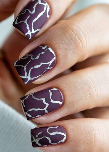 Elegant deep purple nails with abstract silver designs showcasing intricate manicure art.