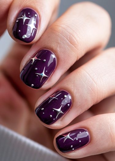 Elegant deep purple manicure with silver star nail art and glossy finish.