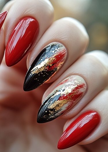 Elegant stiletto manicure with red, black, and gold nail art for a bold statement.