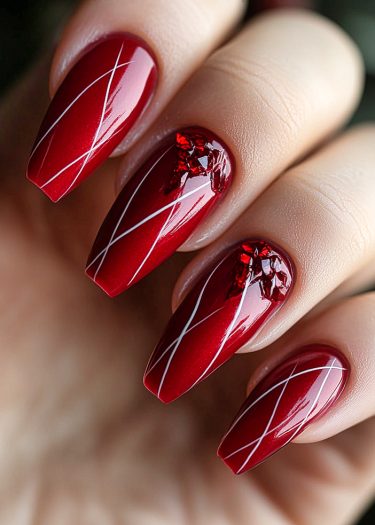 Elegant deep red nail art with geometric patterns and sparkling crystals.