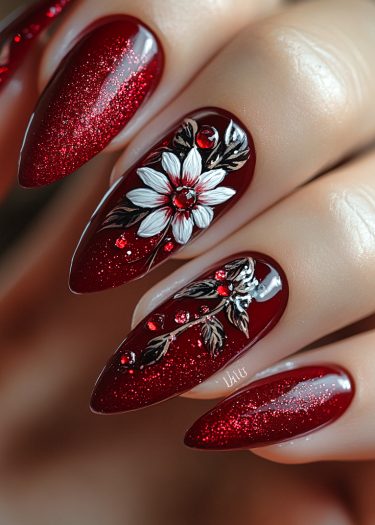 Elegant deep red glitter stiletto nails with intricate floral art and gemstones.