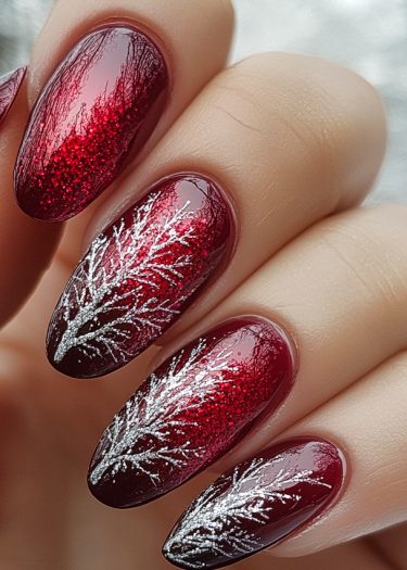 Elegant deep red and silver nail art featuring intricate tree designs for a stylish look.