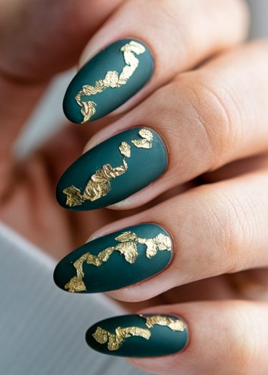 Elegant deep teal matte nails with gold foil accents for a sophisticated nail art design.