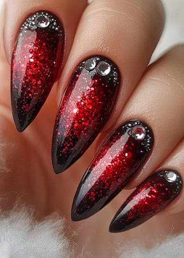 Stiletto red glitter nails with rhinestones, showcasing bold nail art and luxury design.