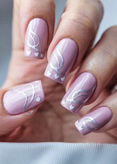 Elegant dusty pink nail art design with white and silver swirls and charming hearts.