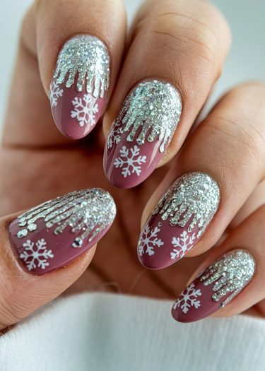 Elegant dusty rose nails with glitter and snowflake designs for a festive winter look.