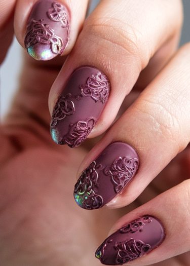 Elegant matte plum nail art with 3D lace patterns and iridescent accents.