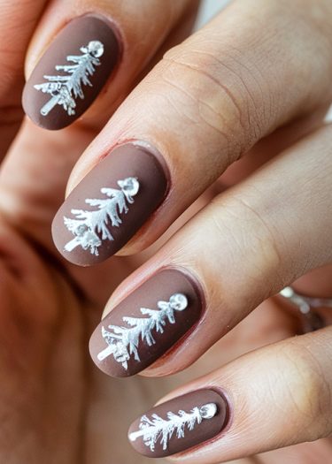 Elegant earthy brown nail art with intricate white Christmas trees for a festive look.